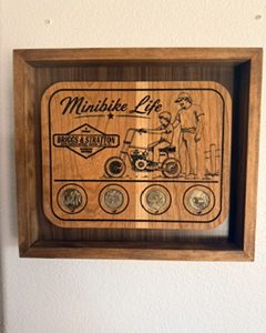 “Minibike Life wooden shadow box plaque with a minibike scene and four engraved coins.