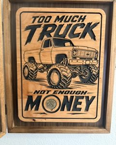 Rustic wooden shadow box plaque featuring a lifted truck with oversized tires, one coin, and the words Too Much Truck — Not Enough Money.